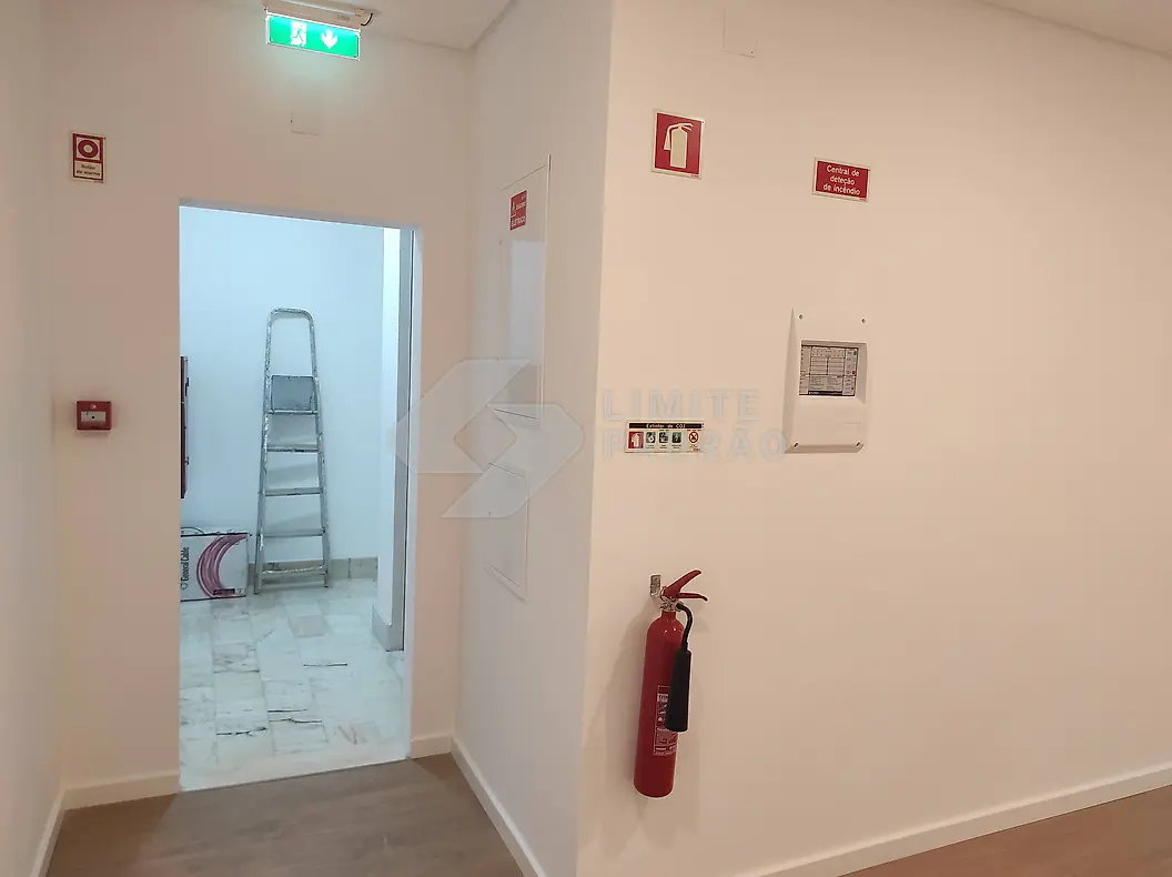 Espaço comercial: corredor com sinalética de segurança e extintores