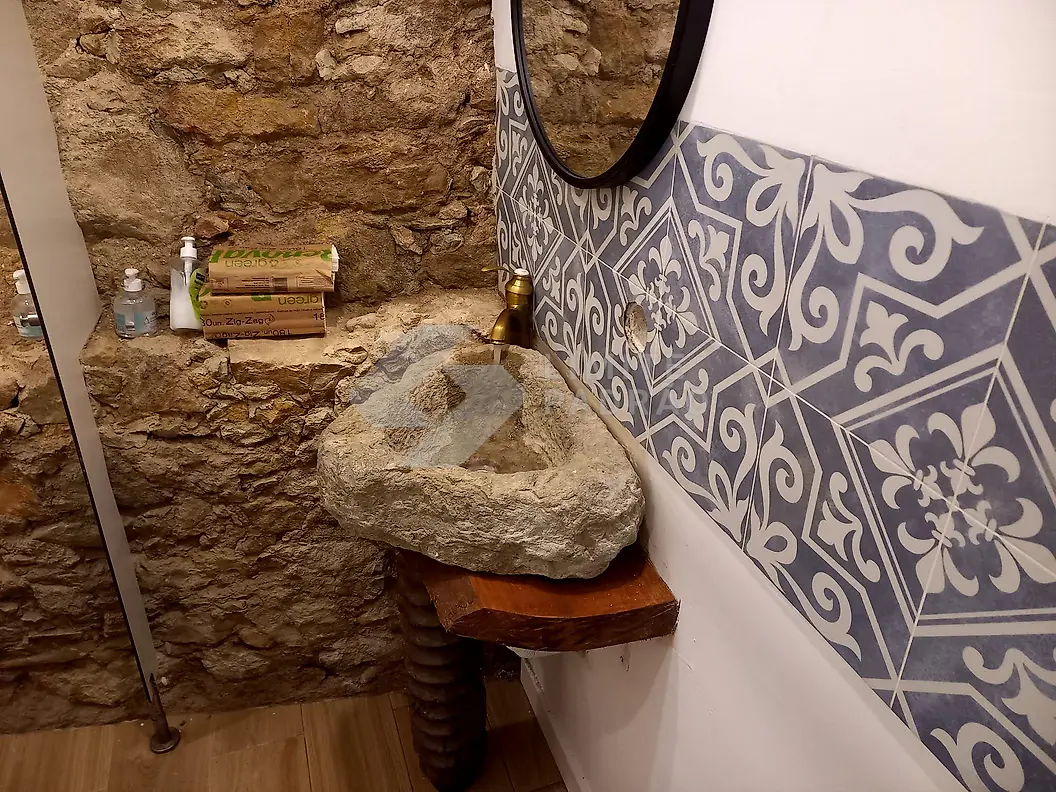 Casa de banho rústica: parede em pedra, lavatório de pedra e azulejo decorativo