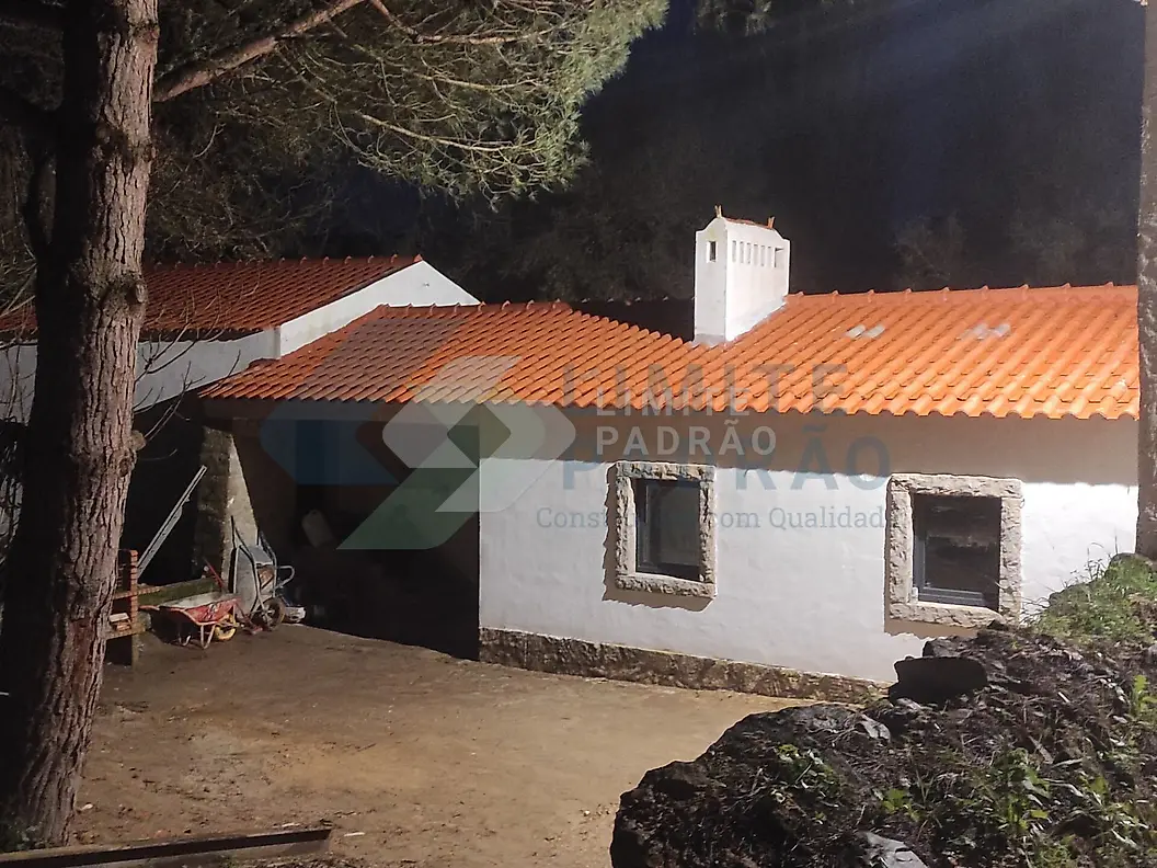 Recuperação de casa rústica: casa de pedra caiada com telhado novo, entre pinheiros
