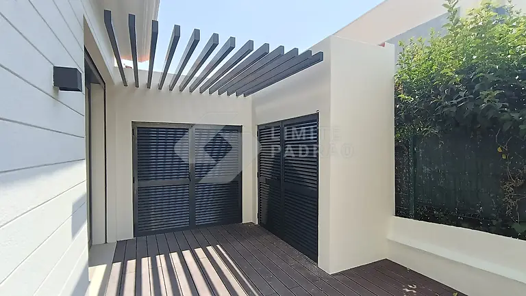 Pátio com pérgola e deck: pérgola de lâminas em alumínio e pavimento em deck compósito, junto à moradia