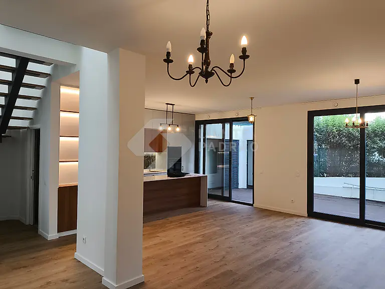 Sala em open space: sala e cozinha num só espaço, lustres e grandes vãos envidraçados para o pátio