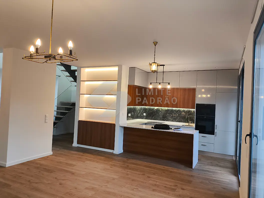 Cozinha com ilha: ilha central, estante iluminada por LED, lustre e escada ao fundo