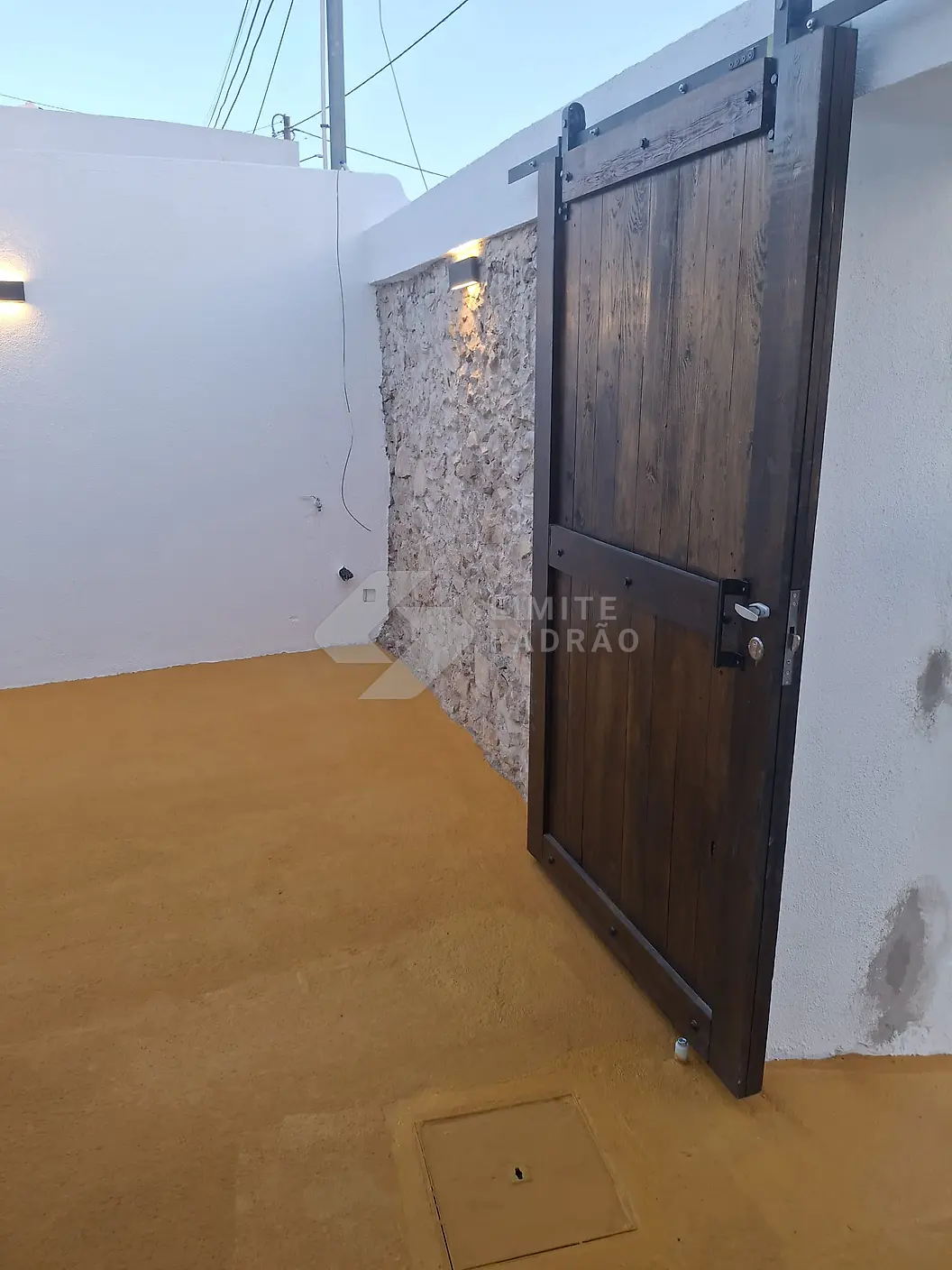 Pátio renovado: porta de correr tipo celeiro em madeira e parede em pedra à vista
