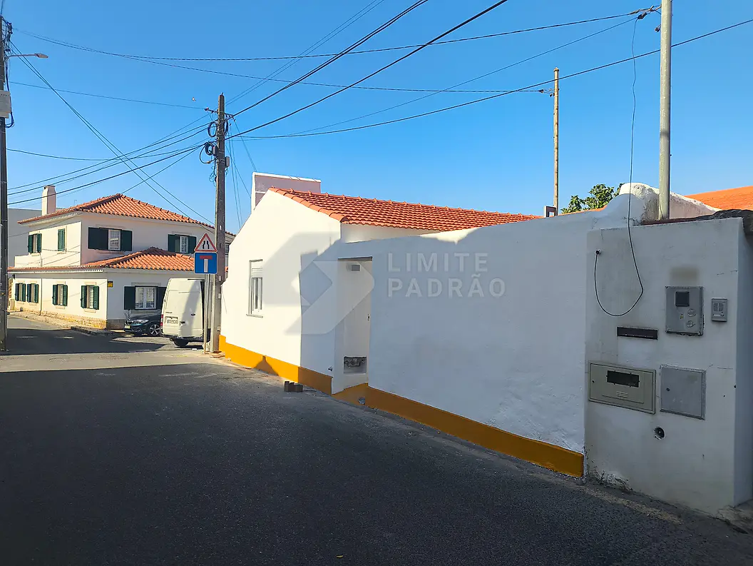 Pintura exterior de moradia: casa térrea com fachada branca e rodapé amarelo, pronta