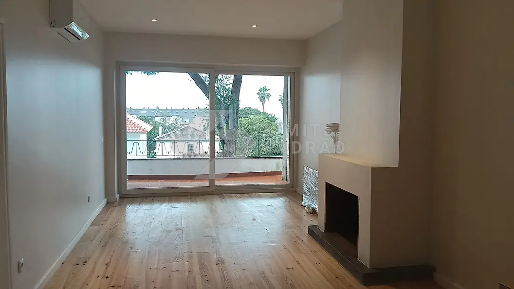 Sala com lareira: lareira, soalho em madeira e varanda com vista para o jardim