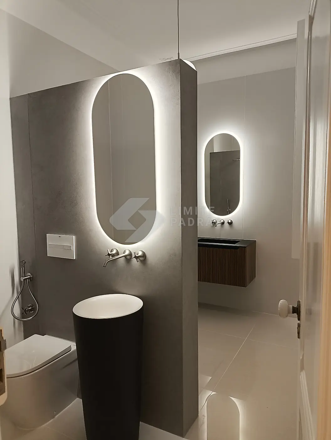 Casa de banho: lavatório de coluna escuro e espelho oval com luz LED
