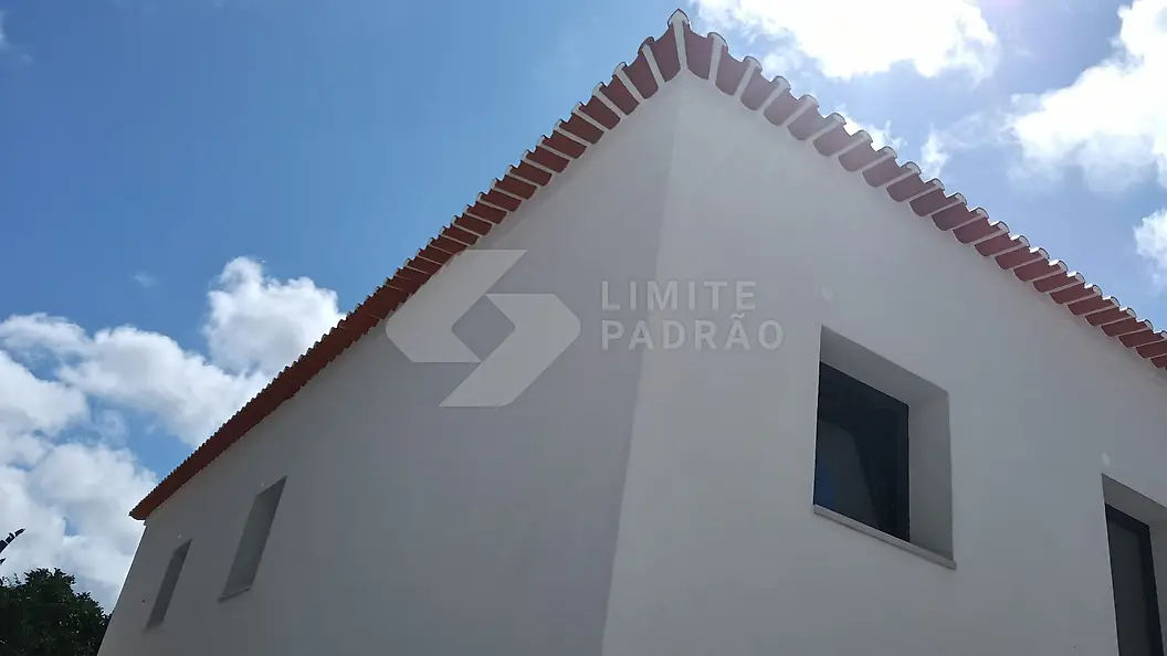 Construção de moradia: alçado lateral de moradia branca com beirado em telha