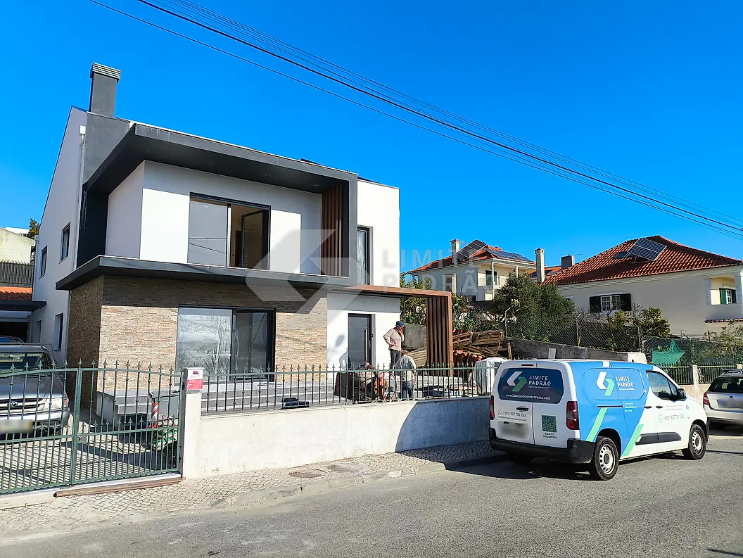 Construção de moradia: moradia nova com revestimento em pedra, gradeamento e a carrinha da empresa