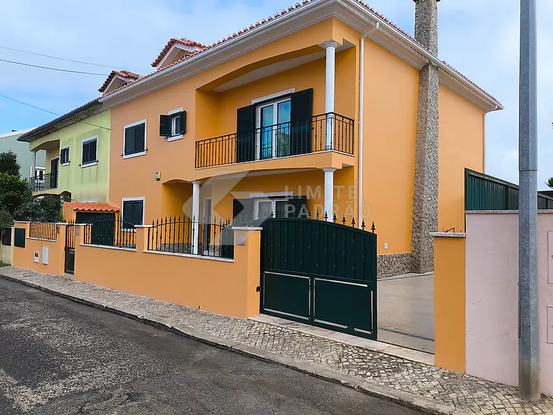 Pintura exterior de moradia: moradia de dois pisos pintada de laranja, com varandas e portão