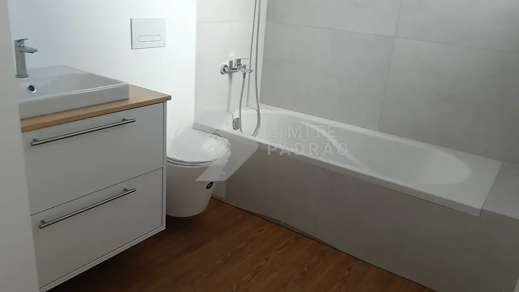 Casa de banho: banheira, móvel branco e lavatório de pousar